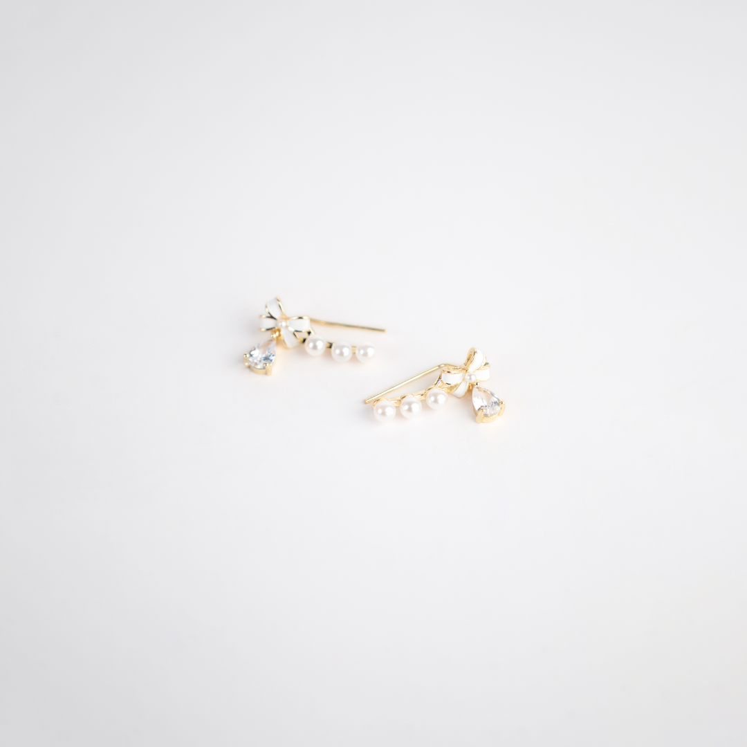 Discover the timeless elegance of our "Elegant Ribbon Earring". These stunning pieces feature a graceful gold-toned ribbon design, adorned with lustrous pearls and sparkling small diamonds. Perfectly balanced between classic and chic, they offer a luxurious touch to any ensemble, making them ideal for both special occasions and everyday glamour.