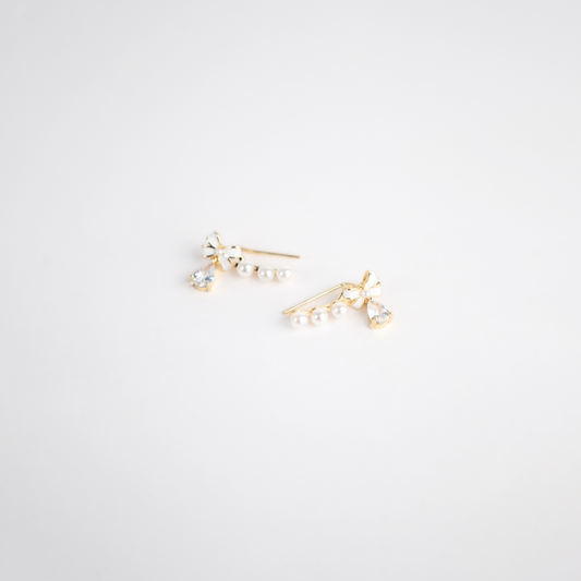 Discover the timeless elegance of our "Elegant Ribbon Earring". These stunning pieces feature a graceful gold-toned ribbon design, adorned with lustrous pearls and sparkling small diamonds. Perfectly balanced between classic and chic, they offer a luxurious touch to any ensemble, making them ideal for both special occasions and everyday glamour.